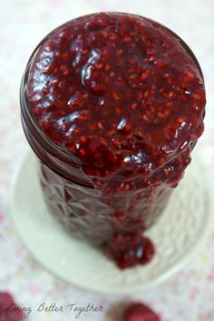 a jar filled with raspberry jam on top of a white plate