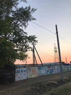 a wall with graffiti on it next to a tree and power lines in the background