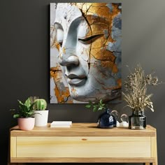 a wooden table topped with potted plants next to a white and gold buddha painting