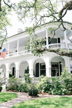 a white house with an american flag on the front porch and balcony balconies