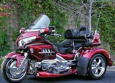 a red motorcycle is parked on the side of the road in front of some bushes