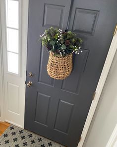 a door with a basket hanging on it's side and flowers in the front