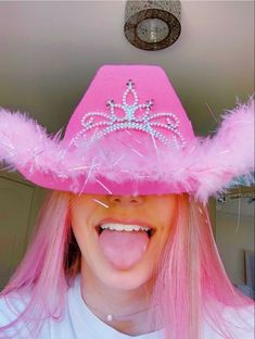 a woman with pink hair wearing a pink and white hat that has a tiara on it