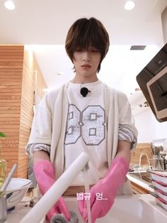 a young man wearing pink gloves is washing his hands