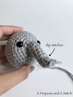 a crocheted elephant is being held up by someone's hand with the string attached to it