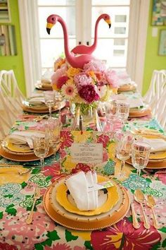 the table is set with pink flamingos and yellow plates, napkins, and place settings