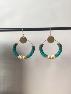 the hoop earrings are made from gold and turquoise glass beads, with a disc in the middle