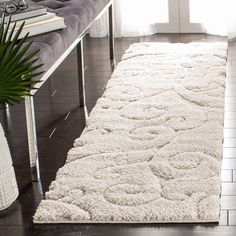 a large white rug on top of a hard wood floor next to a couch and coffee table