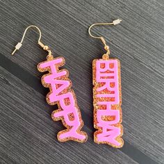 Celebrate joyous moments with these unique acrylic earrings! Our hook dangle earrings feature a charming combination of pink 'happy' and 'birthday' on lustrous gold glitter acrylic. Make a statement with this playful pair, perfect for adding a touch of happiness to a birthday. Handcrafted with care, these earrings are a delightful gift or a stylish addition to your own collection. Embrace the sparkle and spread the cheer with these one-of-a-kind accessories! Pink Novelty Earrings For Party, Pink Drop Earrings For Birthday, Cute Drop Earrings For Birthday, Trendy Red Earrings For Birthday, Birthday Drop Earrings, Pink Novelty Jewelry For Birthday, Playful Pink Earrings For Party, Cute Pink Jewelry For Birthday, Pink Hypoallergenic Party Jewelry