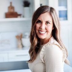 a woman standing in front of a kitchen counter top smiling at the camera with her hands on her hips