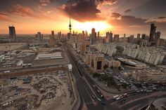 an aerial view of a city with tall buildings and cars in the foreground at sunset