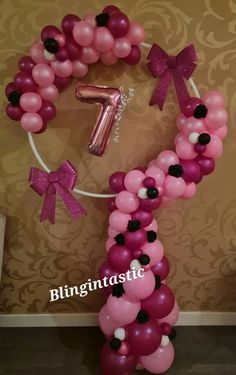 the balloon arch is decorated with pink, black and white balloons that spell it's first birthday