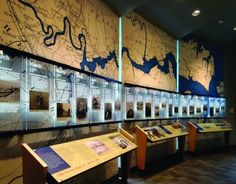 an exhibit with maps on the wall and wooden benches in front of it, along with other displays