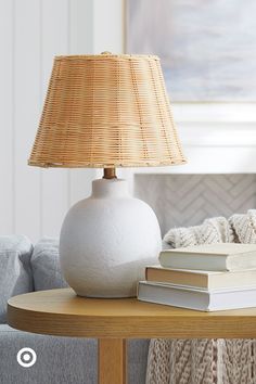 a white vase sitting on top of a wooden table next to a book and lamp