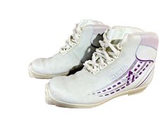 a pair of white ice skates with purple and white designs on the soles