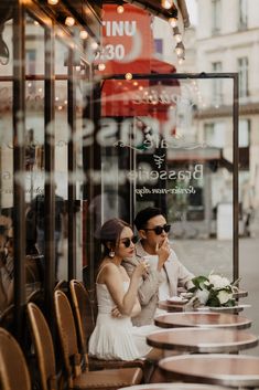 a man and woman sitting at a table in front of a restaurant