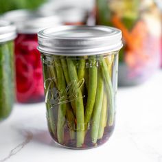 several jars filled with pickled vegetables sitting on a white counter top next to each other