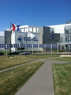 a building with flags on the side of it and grass in front that is very green