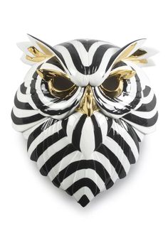 a black and white owl mask with gold accents on it's face, against a white background