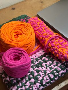 there are many different colored yarns on the table next to an open laptop computer