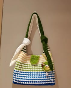 a crocheted handbag hanging on the wall with a green and white handle