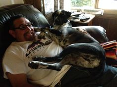 a man laying on top of a couch next to a black and white dog in his lap