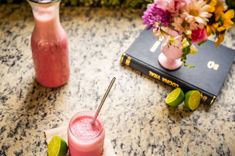 two drinks sitting on top of a table next to a book