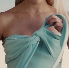 a woman with blonde hair wearing a blue dress and holding onto a green towel over her shoulder