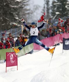 a person jumping in the air on skis while people watch from behind them watching