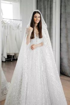 a woman in a white wedding gown and veil posing for the camera with her hand on her hip