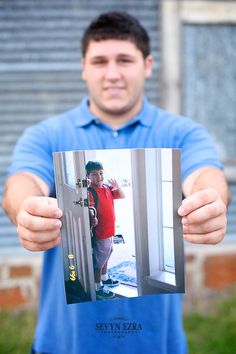 a man holding up a photo of himself in front of an open door with his hand