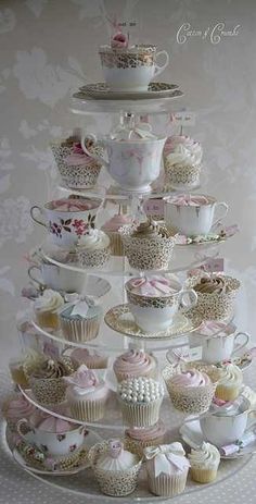 a cake stand filled with lots of cupcakes and teacups on top of each other