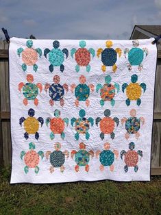 a quilt is hanging on a clothesline in front of a fence with an animal theme