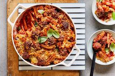 two bowls filled with pasta and meat on top of a wooden cutting board next to other dishes