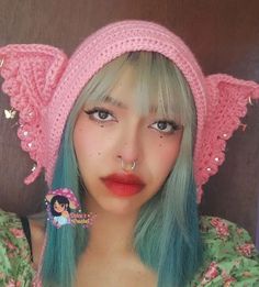 a girl with blue hair wearing a pink hat and piercings on her nose is looking at the camera