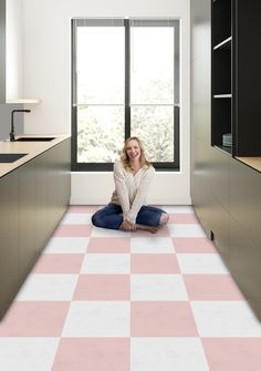 a woman is sitting on the floor in a room with pink and white checkered floors