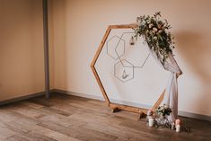 a wedding arch decorated with flowers and greenery sits on the floor next to candles