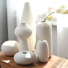 several white vases sitting on top of a wooden table