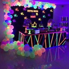 a party with neon lights and balloons on the walls is ready for guests to eat