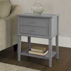 a white night stand with two drawers and a lamp on it next to a couch