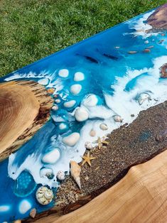 a wooden table topped with lots of blue and white paint on top of green grass