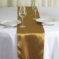 the table is set with white plates and silverware, along with two empty wine glasses