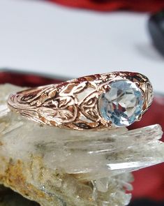 Natural Blue Topaz Ring Description Etched Wedding Design#160 Custom Here we have a Victorian/Edwardian reproduction ring in 14k rose gold with a stunning natural blue topaz gemstone. This full cut round cut genuine blue topaz is 6mm in diameter. The inside of the band is marked 14k for gold. Notice the beautiful floral design of the gold filigree setting. This is a lovely rendition of an Antique filigree wedding ring, and it is made ready to wear. A gift ring box is included and all rings are s Luxury Intricate Design Topaz Wedding Ring, Luxury Vintage Topaz Ring Gift, Luxury Topaz Ring With Intricate Design For Formal Events, Diamond Cut Blue Topaz Ring For Wedding, Victorian Blue Topaz Ring For Anniversary, Heirloom Blue Topaz Diamond Cut Ring, Heirloom Blue Topaz Ring With Diamond Cut, Rose Gold Topaz Ring For Wedding, Rose Gold Topaz Wedding Ring