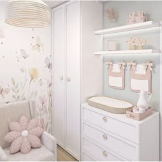 a baby's room with white furniture and flowers on the wall