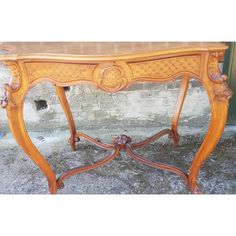 an antique wooden table with carvings on the top and bottom, sitting in front of a brick wall