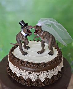 a dinosaur wedding cake topper with a bride and groom