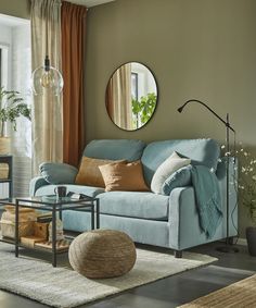 a living room filled with furniture and a round mirror on the wall above the couch