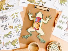 a clipboard with frog pictures on it next to other paper and crafting supplies