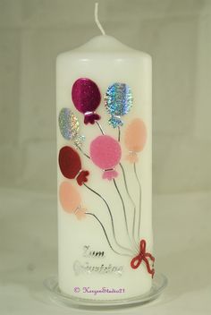 a white candle with balloons on it