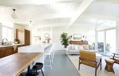 an open concept kitchen and living room with white walls, wood flooring and wooden furniture